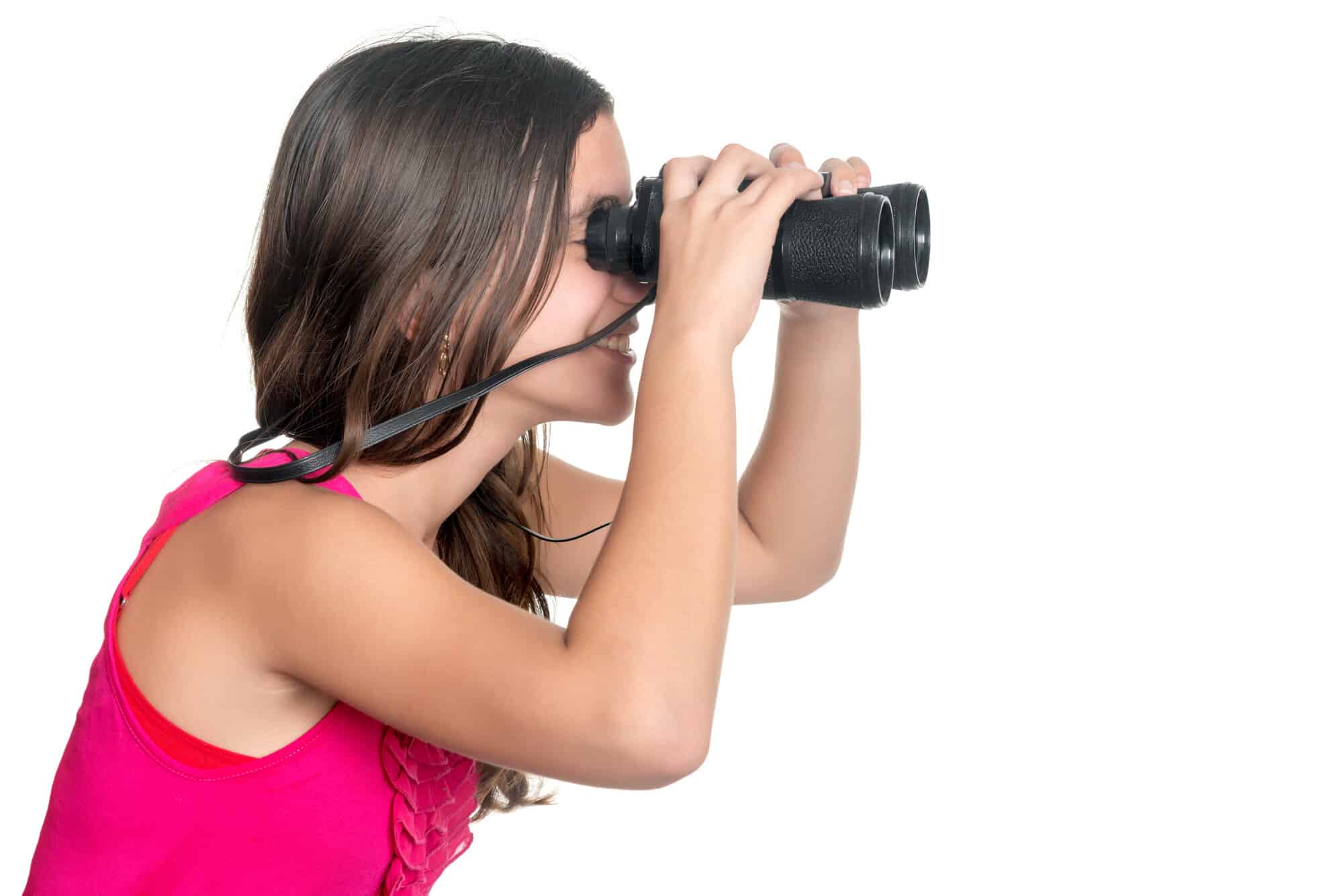 Beautiful teenage girl looking through a pair of binoculars isolated on white